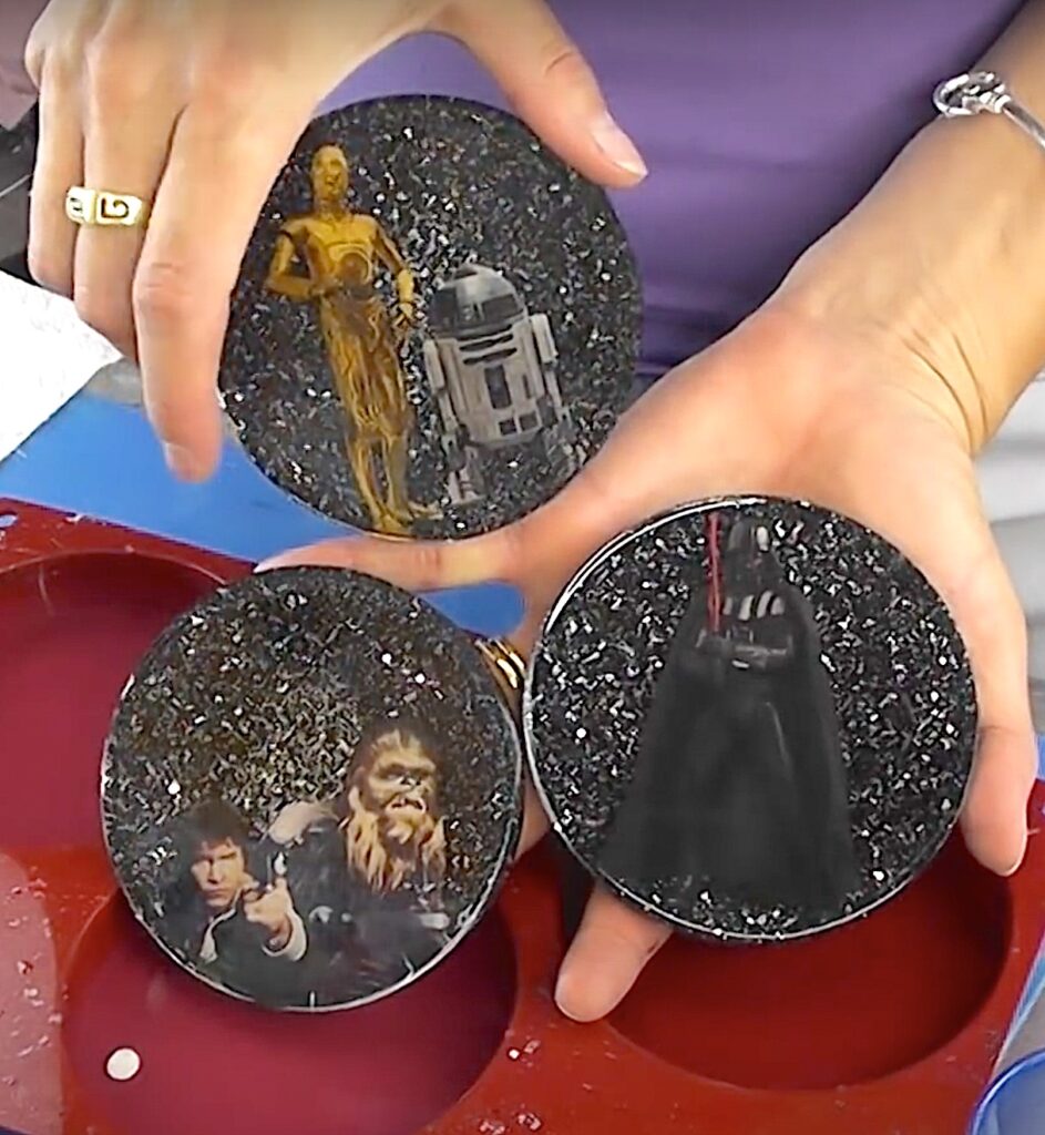 Star Wars project | Three Star Wars coasters with black glitter backgrounds. One with Darth Vader. One with Han Solo, Chewbacca and Yoda. One with R2 D2 and C3PO.