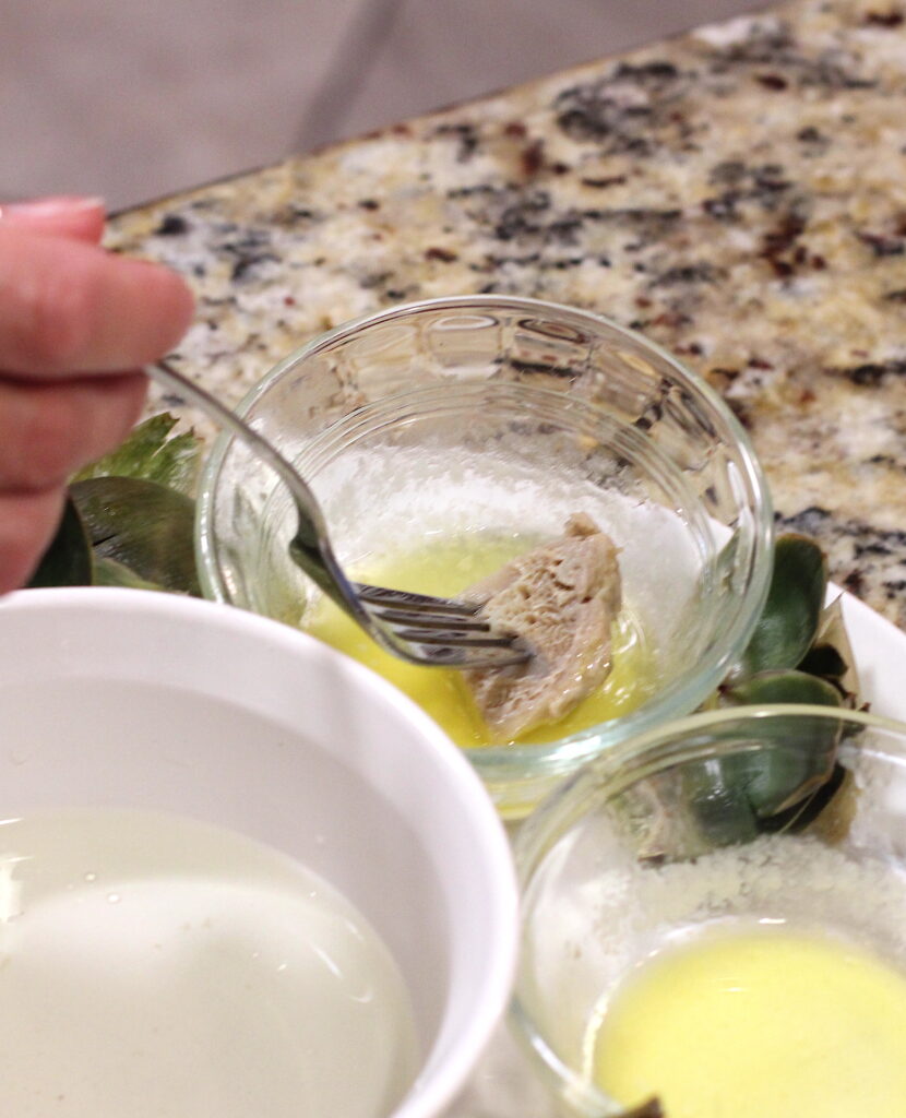 Dip artichoke heart into melted butter