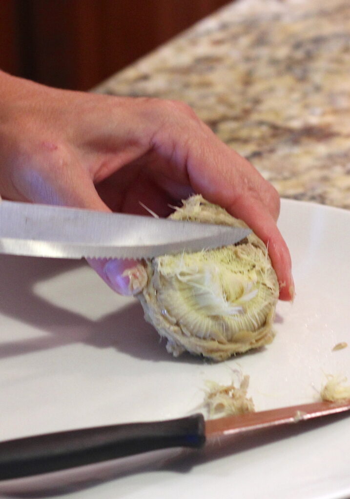 Scrape artichoke center choke off with a knife