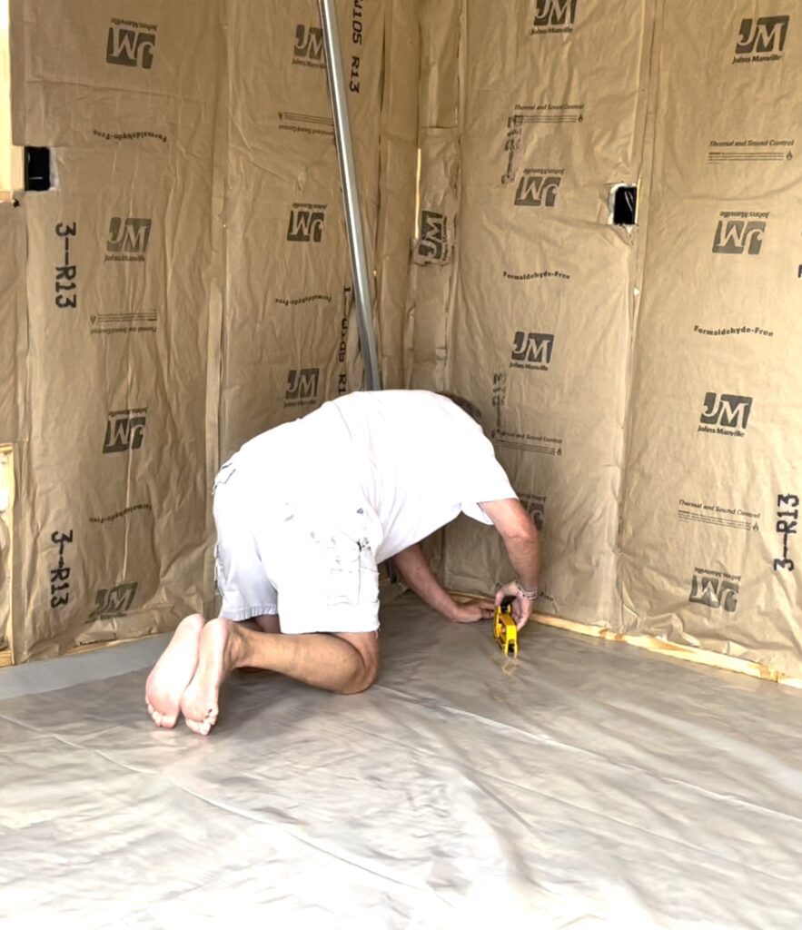 Greg stapling plastic sheet on shed building floor