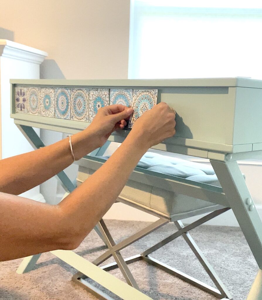 Applying tile stickers to front of desk