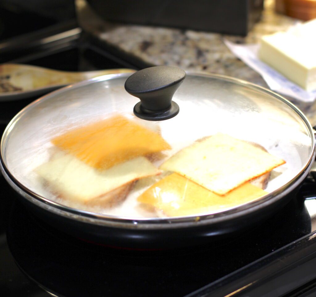 Put lid on over the the grilled cheese sandwiches in the pan to melt the cheese