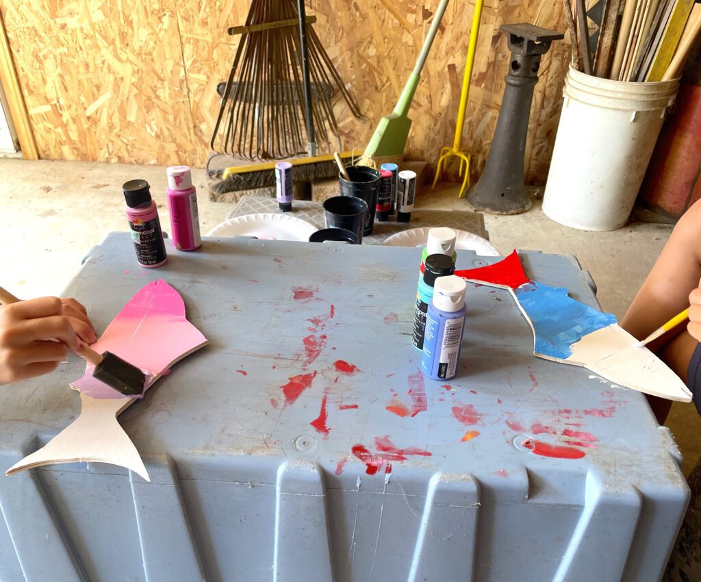 Wood fish being painted pink and blue and red
