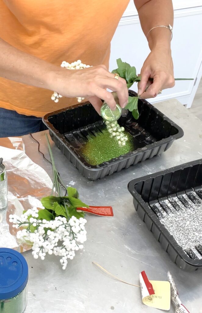 Adding glitter to berry to add to the outdoor Christmas decorations DIY