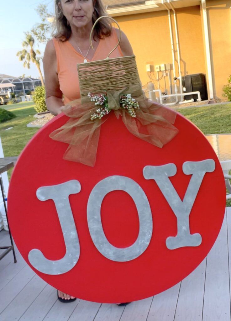 Mona holding the oversized Christmas ornament