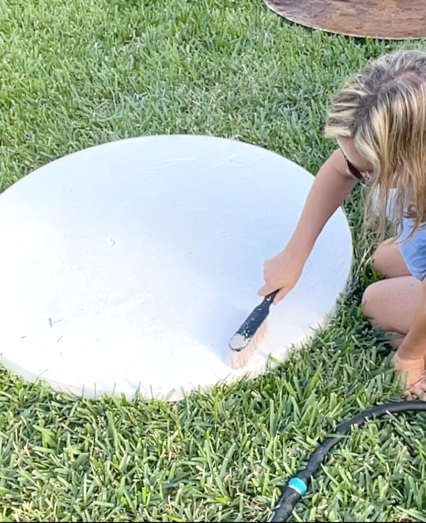 Using scrub brush to clean the tabletop with soap and bleach