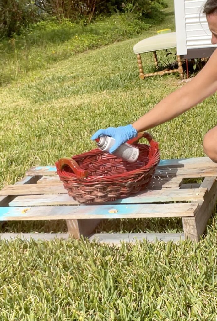 Spray painting red basket for pine cone Christmas craft decoration