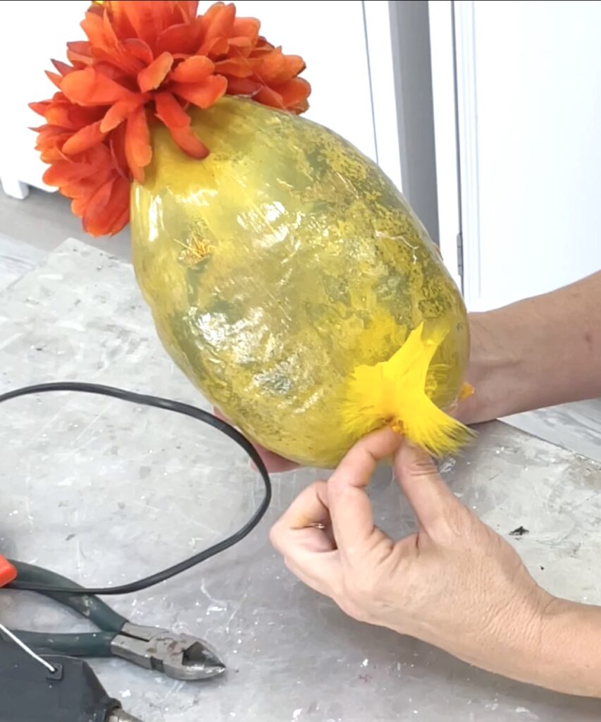 Gluing yellow tail feathers onto the back of the coconut chick bird craft