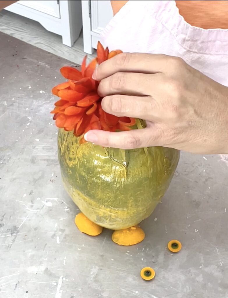 Easter painting ideas - coconut painted yellow, fake flowers glued to the the top of the coconut to create a plume