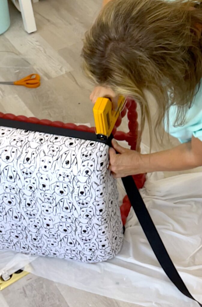 Stapling grossgrain ribbon as trim around the black and white dog fabric