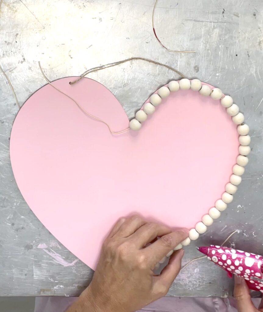 Gluing wood beads onto the dollar tree heart