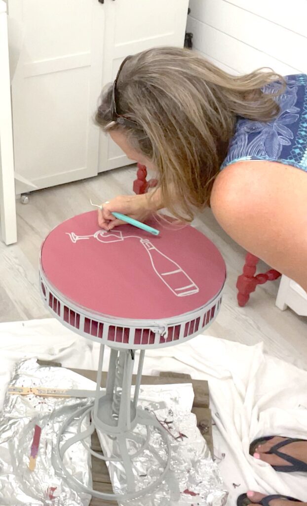 peeling the vinyl off of the painted table top to reveal the wine bottle design