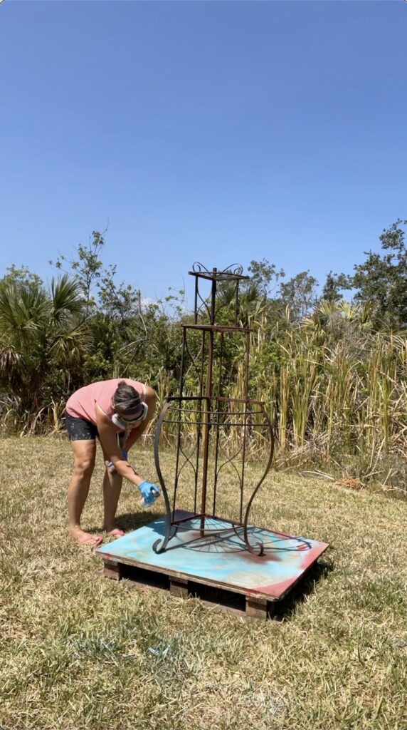 Spraying rusty metal primer onto the corner rack for the front porch