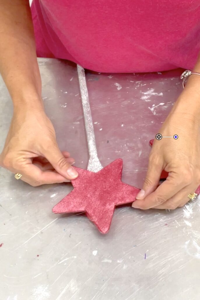 Gluing the red star to the end of a wooden spoon