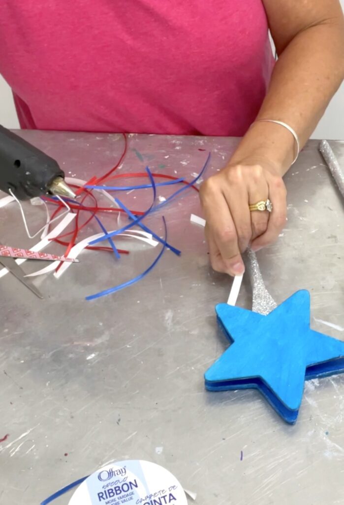 Gluing red white and blue ribbons to the star wands