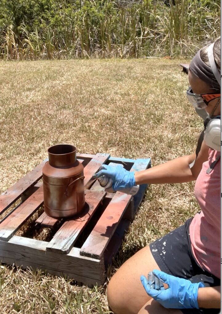 Spraying the milk jug with Rust-Oleum rusty metal primer