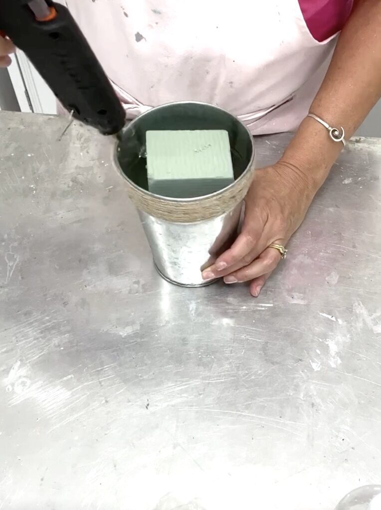 Gluing the floral foam into the bucket for the bridal shower centerpiece