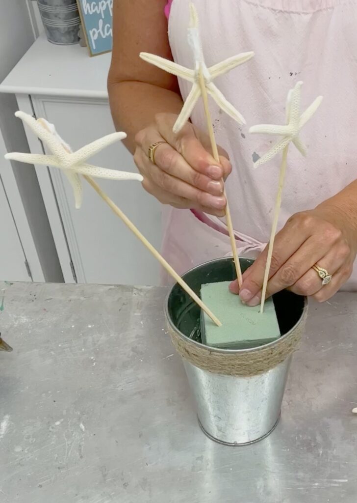 Sticking starfish on skewers into the floral foam for the wedding shower centerpiece