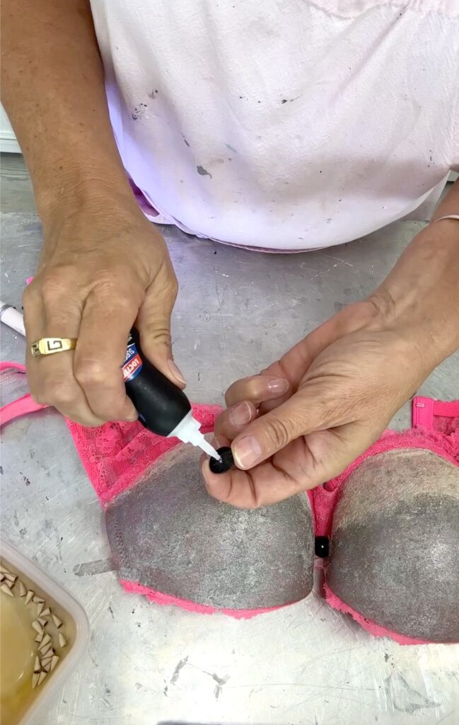 Gluing eyes on the bra for bra pong bridal shower game