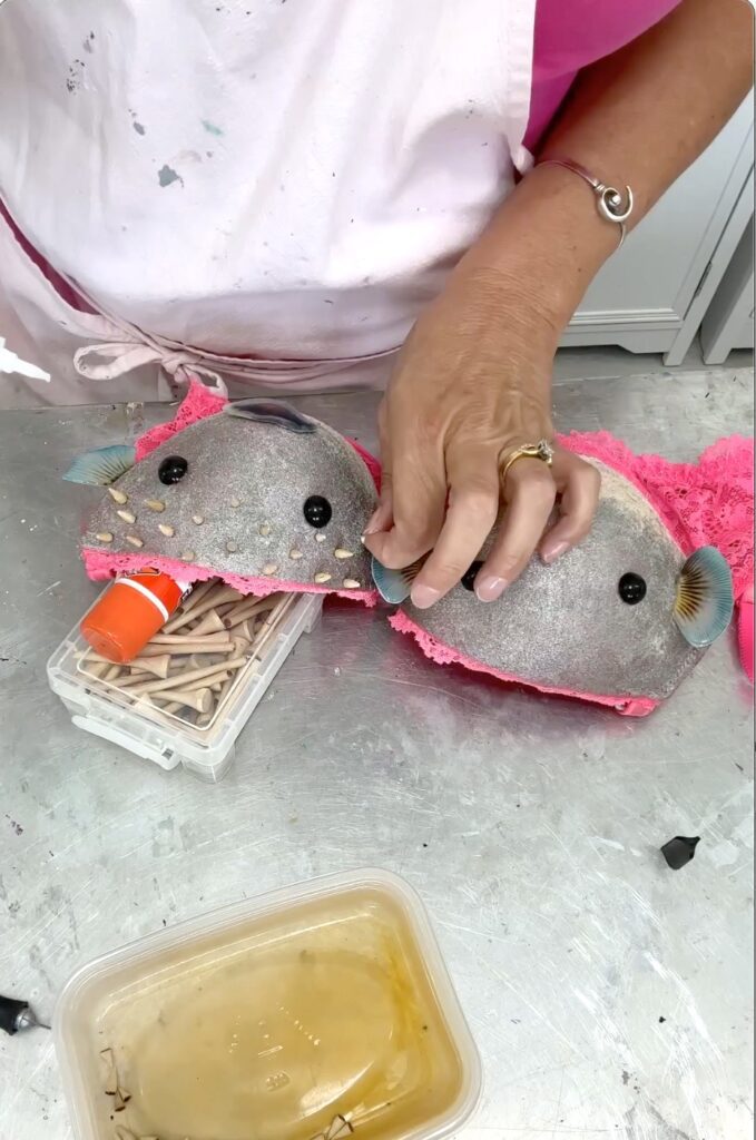 Gluing on golf tee tips as spikes on the pufferfish for the bridal shower bra pong game