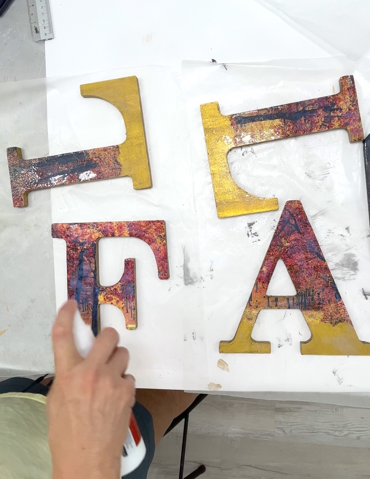 Using Mod Podge Spray in gloss to seal the decoupaged wood letters