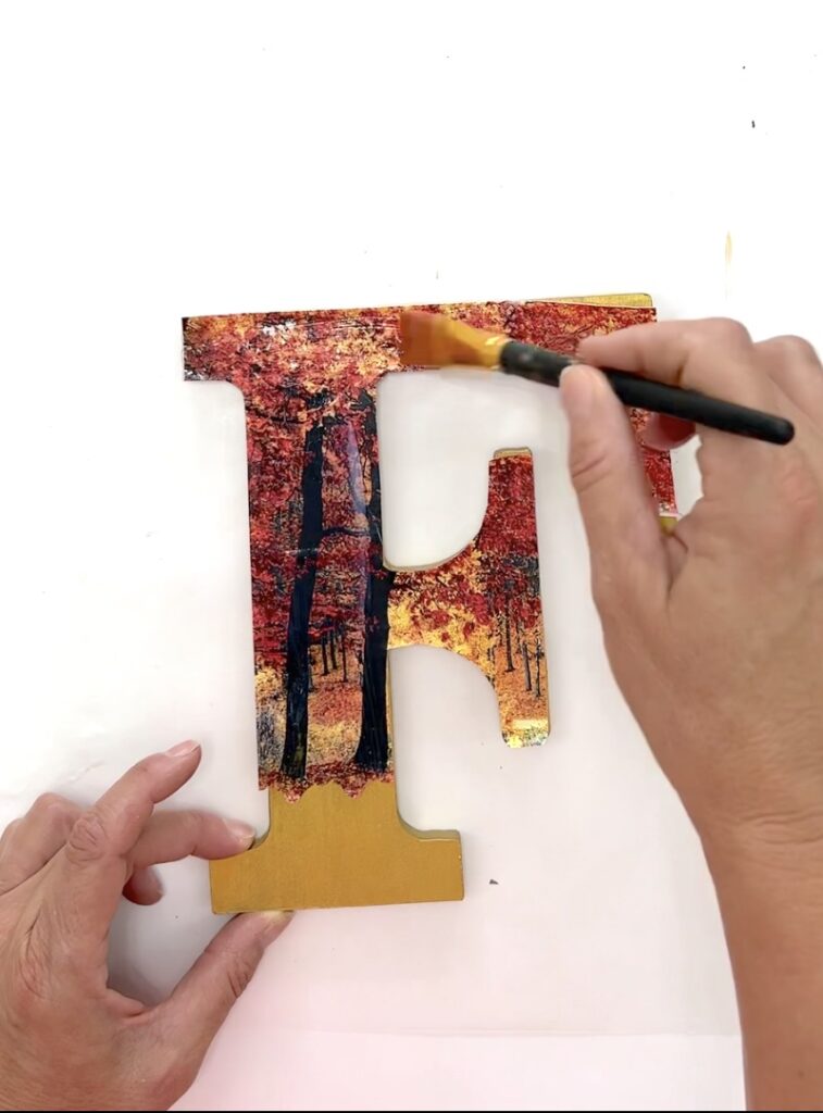 Using Mod Podge to decoupage the fall scene onto the F wood letter