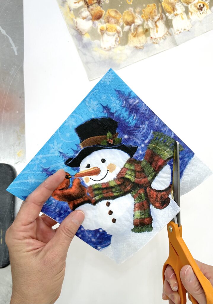 Cutting out a snowman Christmas napkin to decoupage onto ornament