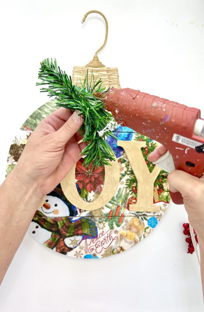 Hot gluing greenery onto the decoupage napkins ornament