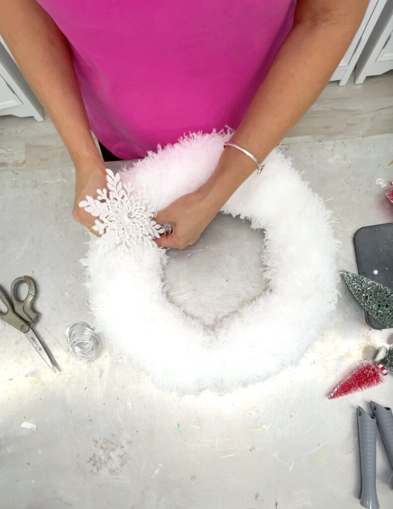 Adding a snowflake ornament to the wreath