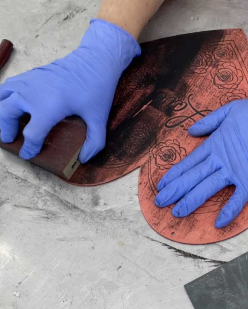 Using a sanding block is distressed heart to make the engravings pop