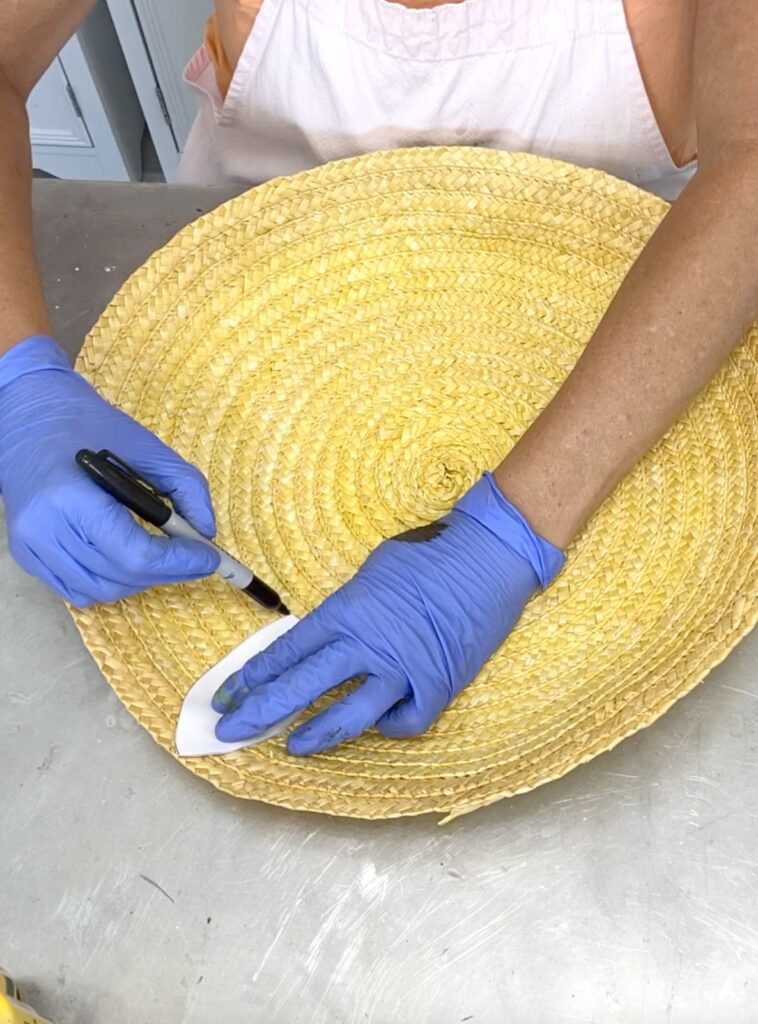 Tracing flower petal onto the flat basket for thrift store craft