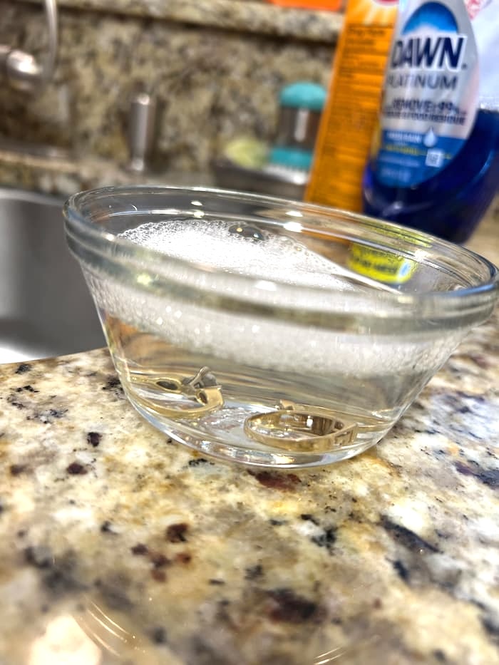 Bowl with suds and jewelry soaking demonstrating how to clean jewelry
