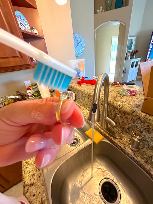 showing how to clean jewelry with a toothbrush