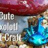 Cute axolotl pet craft teal in color and sitting in rocks under a mushroom