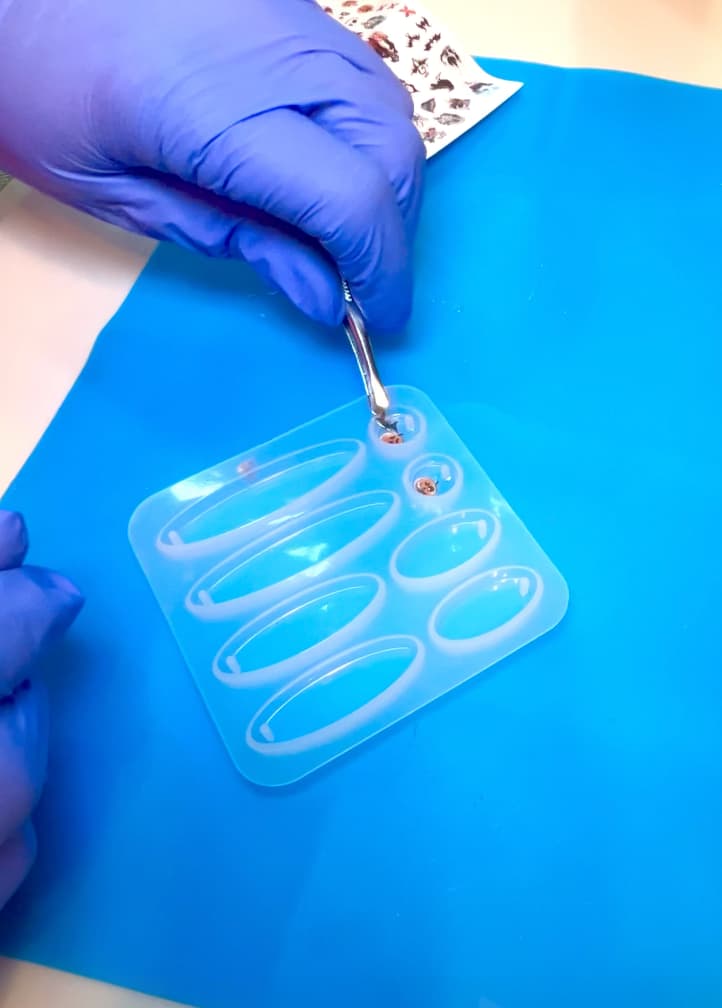 Placing a nail sticker art bat into the resin earring mold