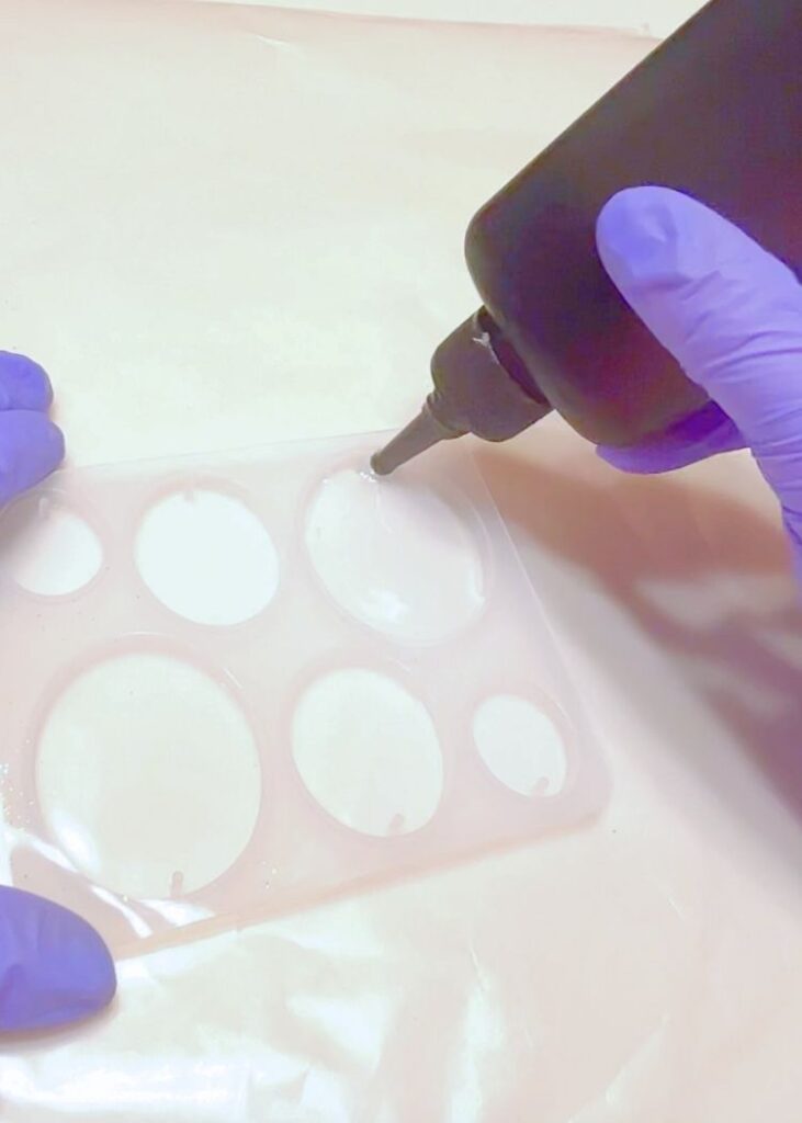 adding UV resin to an oval silicone charm mold