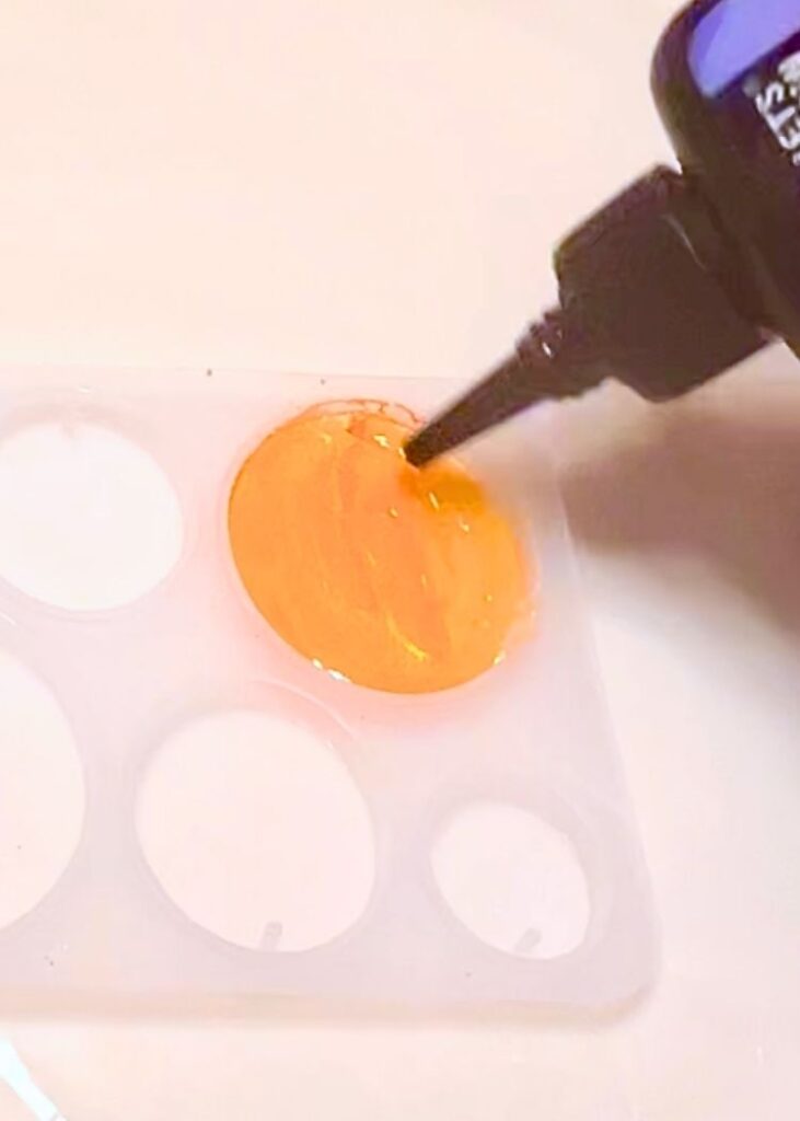 adding a layer of UV resin to seal the paint and pigment powder for the resin pumpkin charm