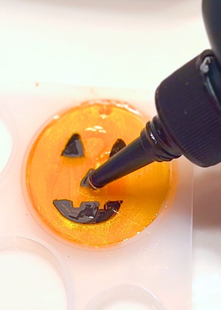 adding a layer of UV resin to seal the painted face for the resin pumpkin charm