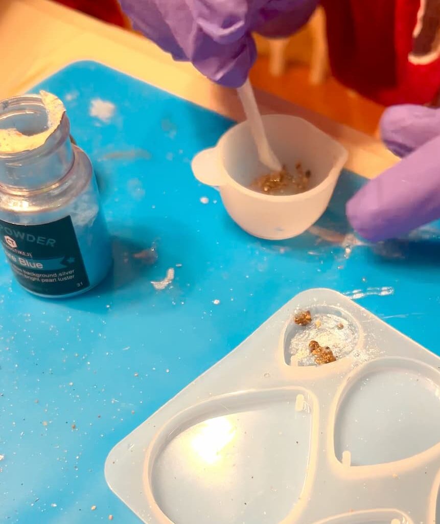 putting resin and sand mixture onto earrings