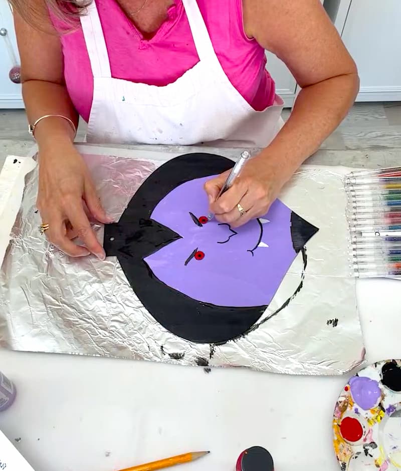 Using glitter gel pens to outline Dracula's features