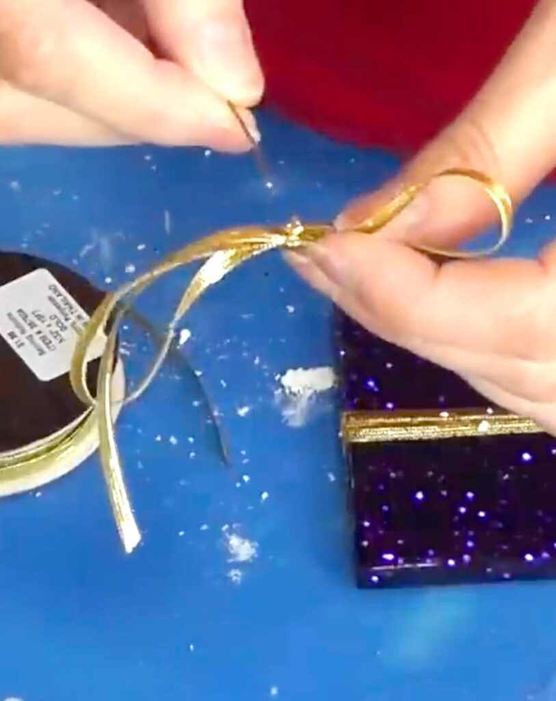 Adding wire to the gold bow for the Christmas present