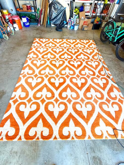 Orange and white wool rug in the garage waiting to be show how to clean rugs