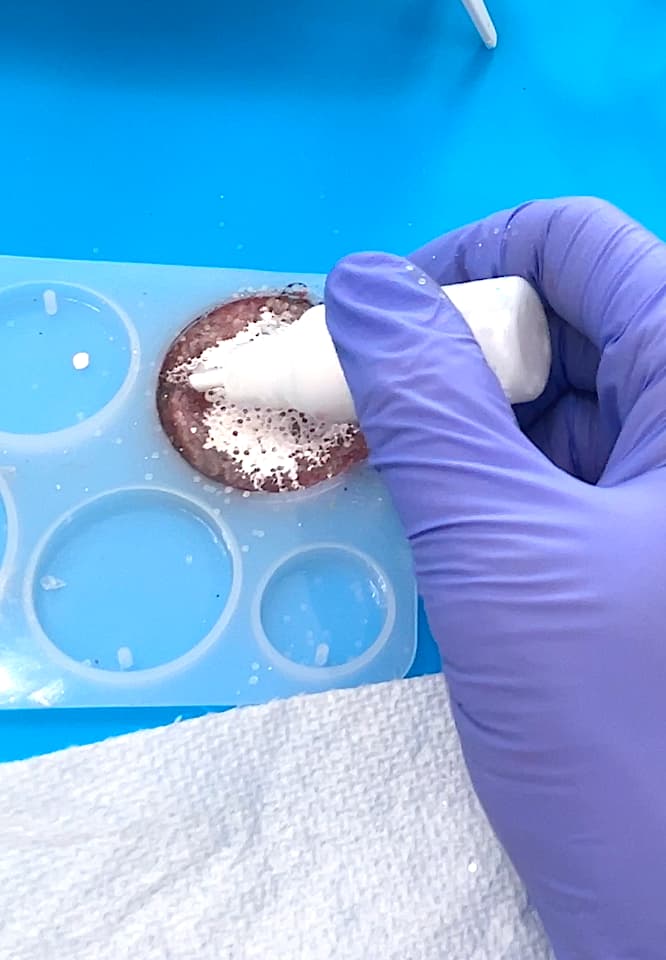 Adding white alcohol ink onto the Christmas charm to create the background for the penguin tattoo