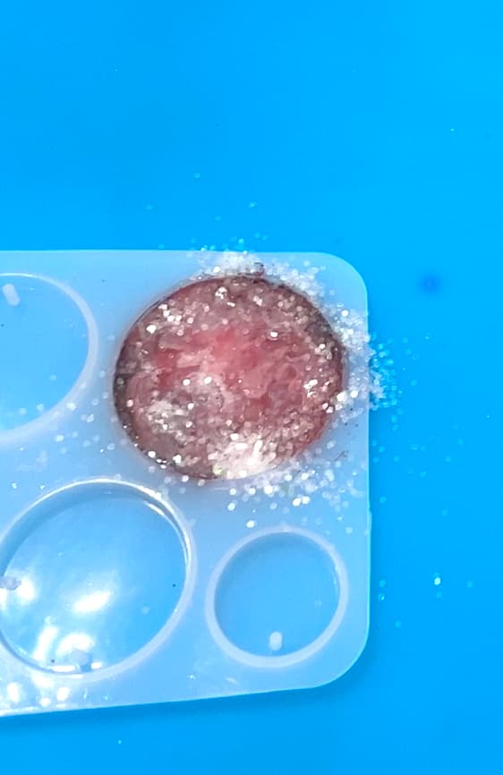 Sprinkled glitter onto the Christmas charm to prepare it for the penguin tattoo