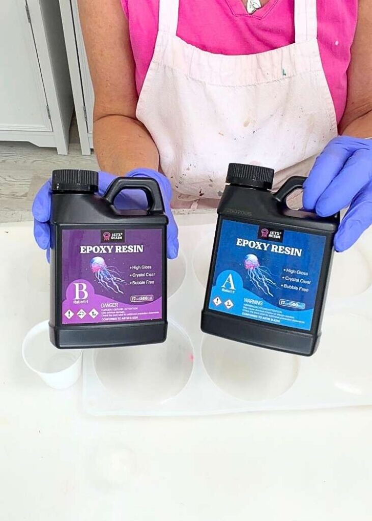 Holding Let's Resin epoxy resin bottles, Part A and Part B