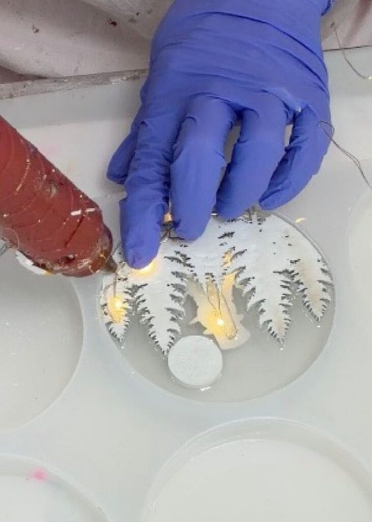 Hot gluing fairy lights to the back of the snowman decor