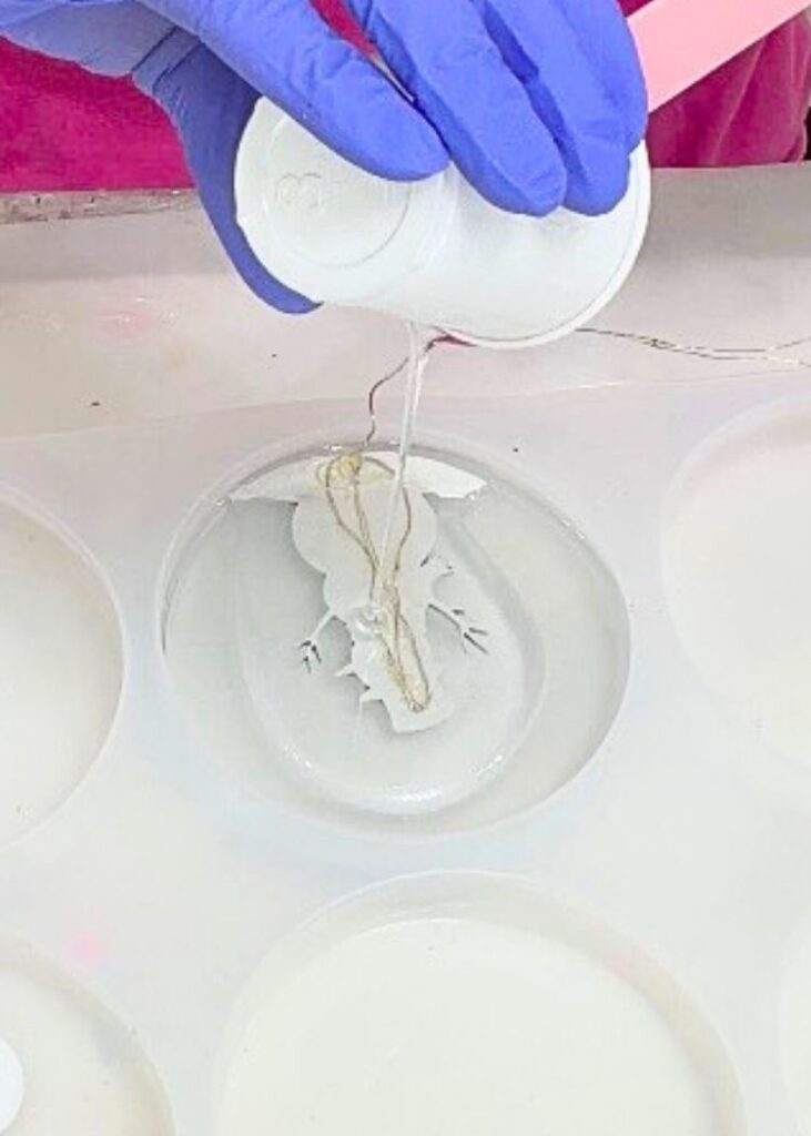 Pouring clear resin snowman with fairy lights on the back