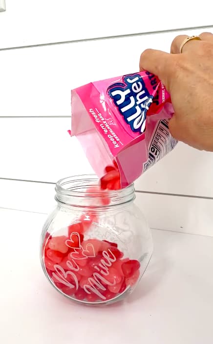 Pouring candy into the glass Valentine's Day craft candy jar