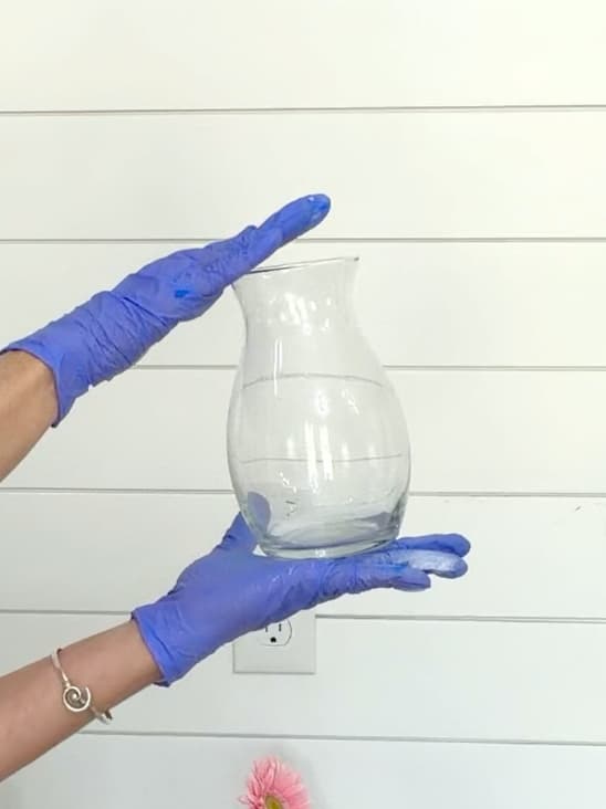 Before photo of clear dollar tree vase in two gloved hands