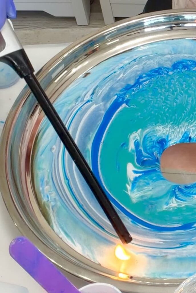 Lighter being used to pop bubbles on the resin ocean art tray